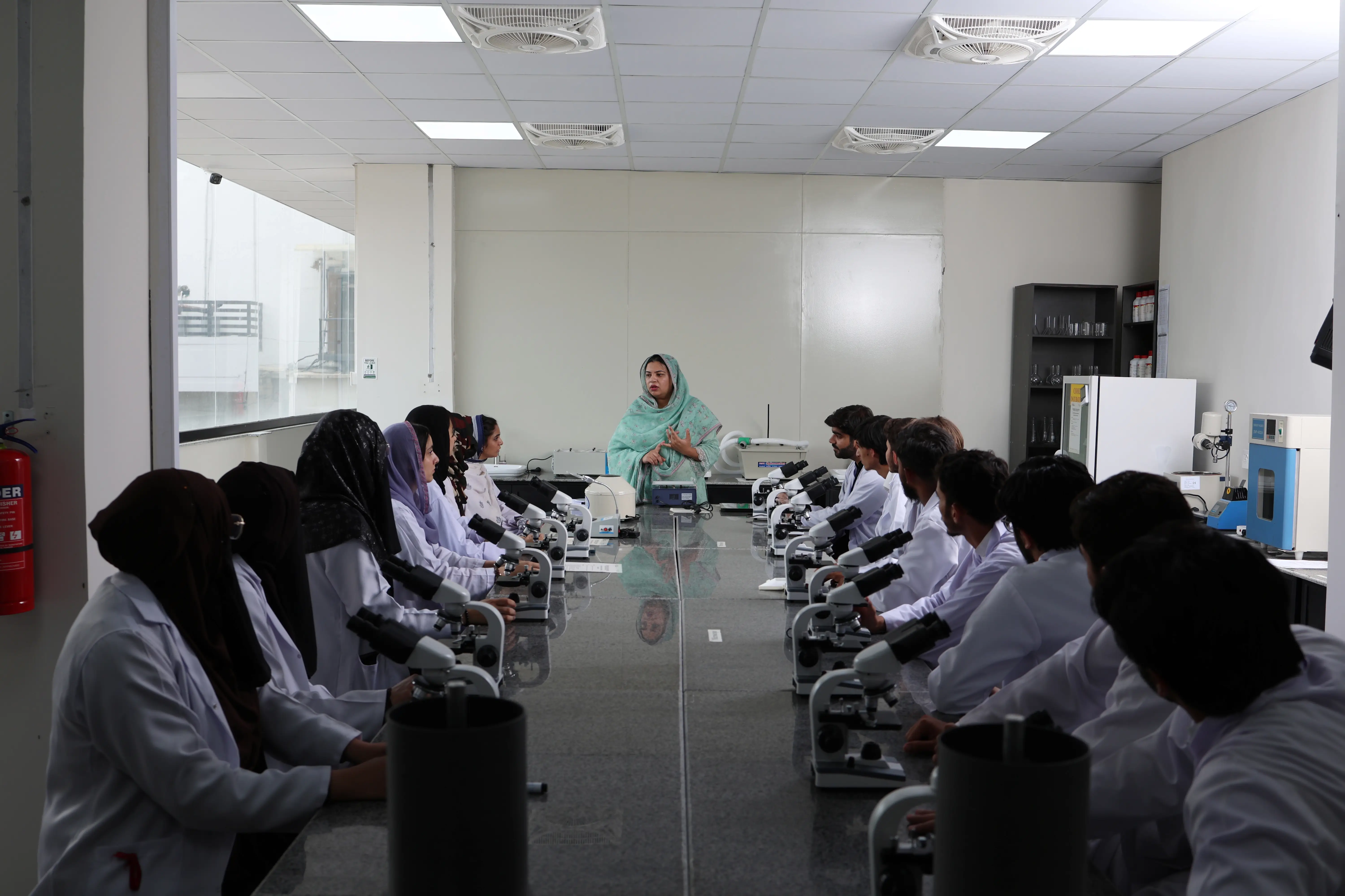 University pharmacy students engaged in practical learning with advanced lab equipment and faculty supervision